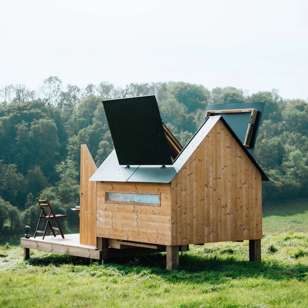 Cabane Hut'Op ouverte avec terrasse dans un champ sous un beau soleil vue arrière